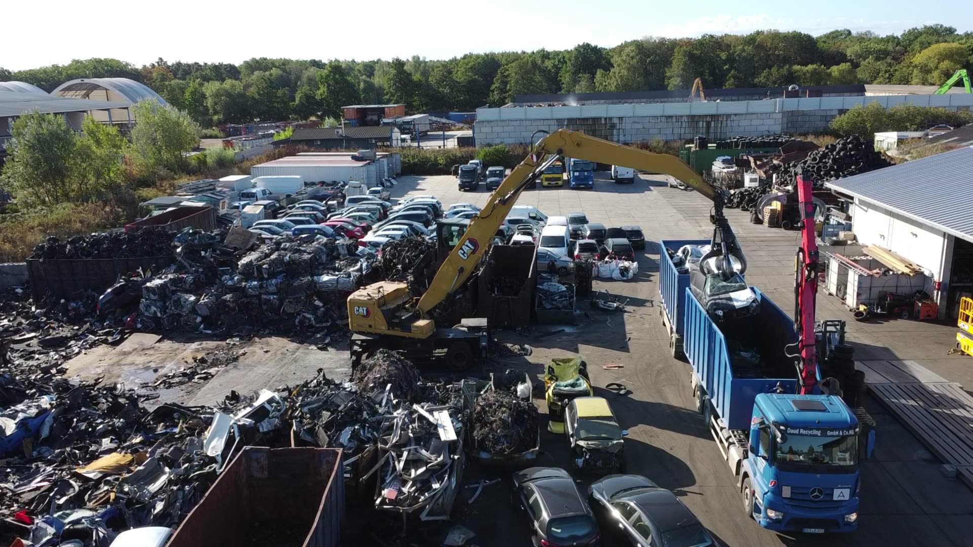 CAT-Umschlagbagger belädt auf dem Betriebshof in Lustadt einen Lkw von Daud Recycling mit Altmetall, Luftaufnahme